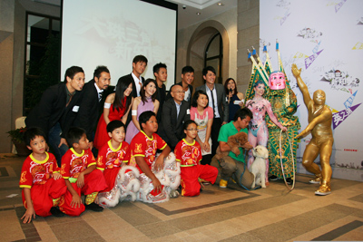 On the right of Law Ka Ying is the Winner of the Youth Kam Cha Competition 2010 (Hong Kong-Style Milk Tea), Ms. Wong Cui Yee; the 5 young men in red in the front row are members of the Lion and Dragon Dance Team of Hong Kong’s Ha Tak Kin Martial Arts Society; fourth from right, front row, is the founder of Daniel Dog Training, Mr. Daniel Tang; third from right is a cast member of Macau’s Cirque Du Soleil; second from right is an Electric Trio performer from Taiwan; first from right is Goldie, the show’s mascot. 
