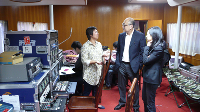 	Mr. Kit Szeto and Ms. Ceci Chuang, Project Director of Dim Sum TV (right) visiting the broadcast control room and talking with the Guangdong Television Sports Channel production team about their Asian Games coverage.