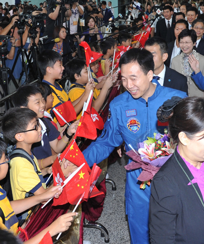 Crew commander Jing Haipeng shaking hands with a student, one of thousands of people lining the streets to welcome the astronauts.   
